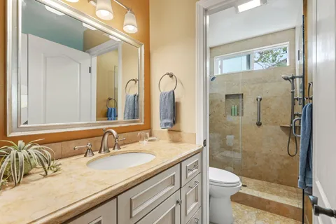 a bathroom with a granite countertop sink mirror vanity and toilet