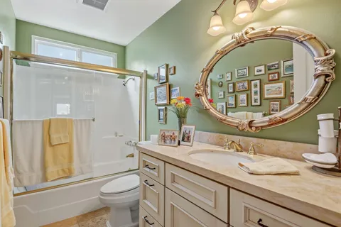a bathroom with a granite countertop toilet a sink a mirror a vanity and a shower