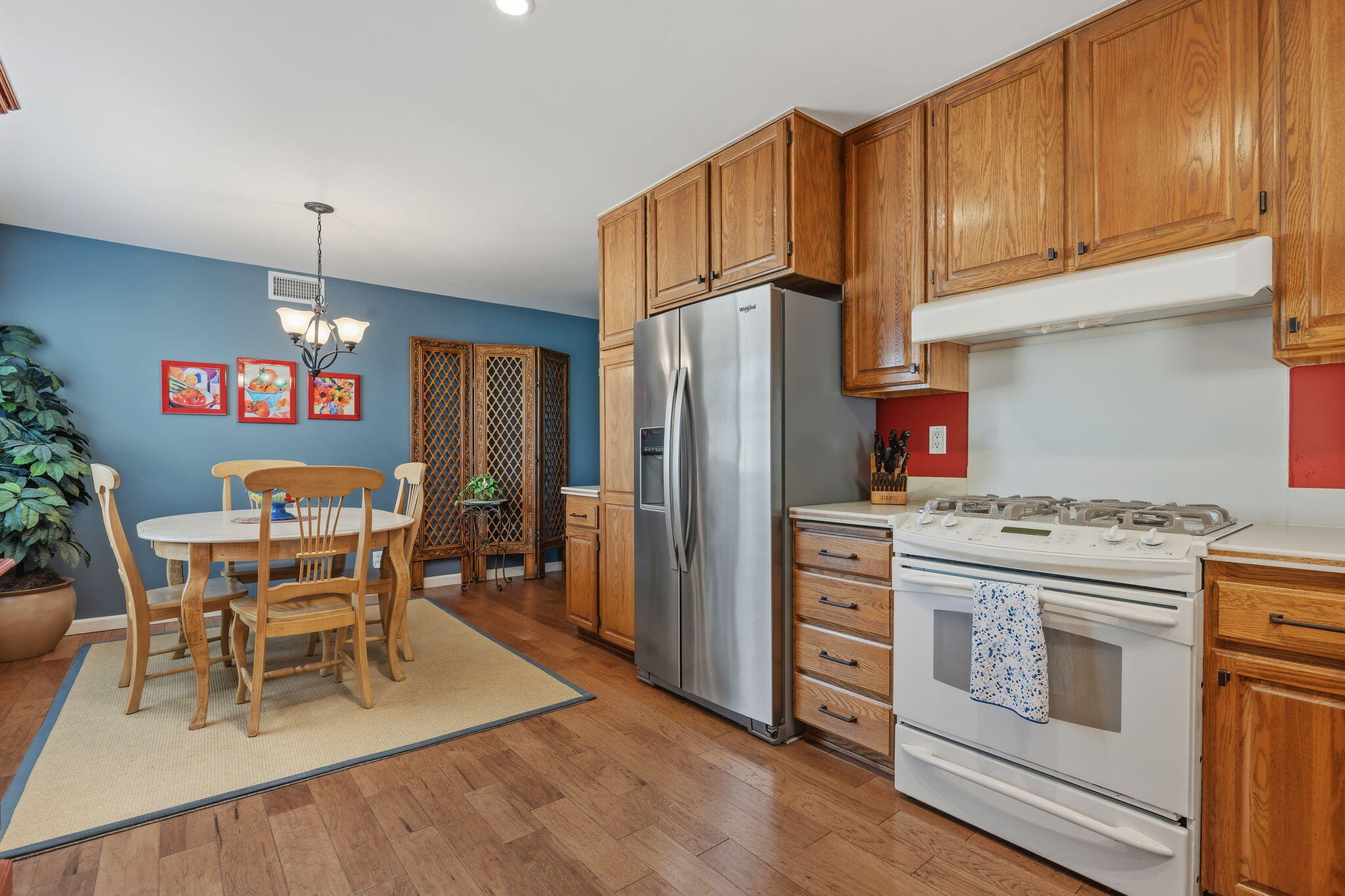 6020 Paseo Palmilla Goleta, CA 93117 - Photo 9 of 33 a kitchen with stainless steel appliances granite countertop a refrigerator a stove top oven a dining table and chairs with wooden floor