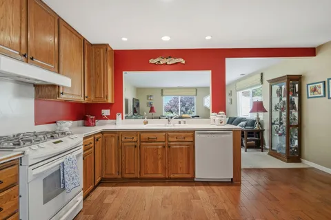 a kitchen with stainless steel appliances granite countertop a stove a sink dishwasher and a refrigerator with wooden floor