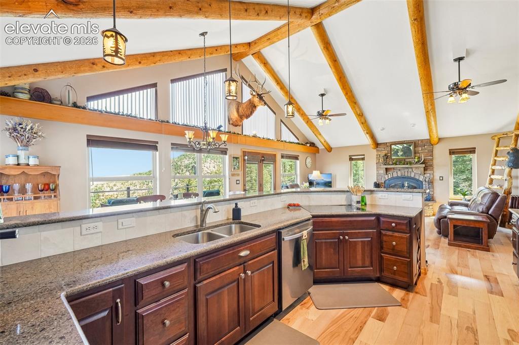 858 Oak Ridge Road Manitou Springs, CO 80829 - Photo 18 of 50 Open concept kitchen with quartz counter tops, matching stainless appliances, rustic cherry cabinetry, a breakfast bar and a wine rack all surrounded by solid hickory flooring