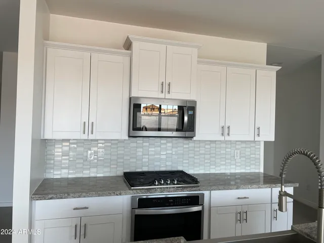 a kitchen with granite countertop white cabinets and stainless steel appliances