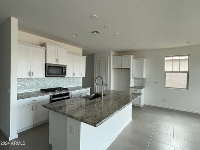 a kitchen with stainless steel appliances granite countertop a sink a stove top oven a counter space and cabinets