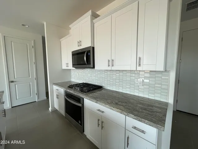 a kitchen with granite countertop white cabinets and stainless steel appliances