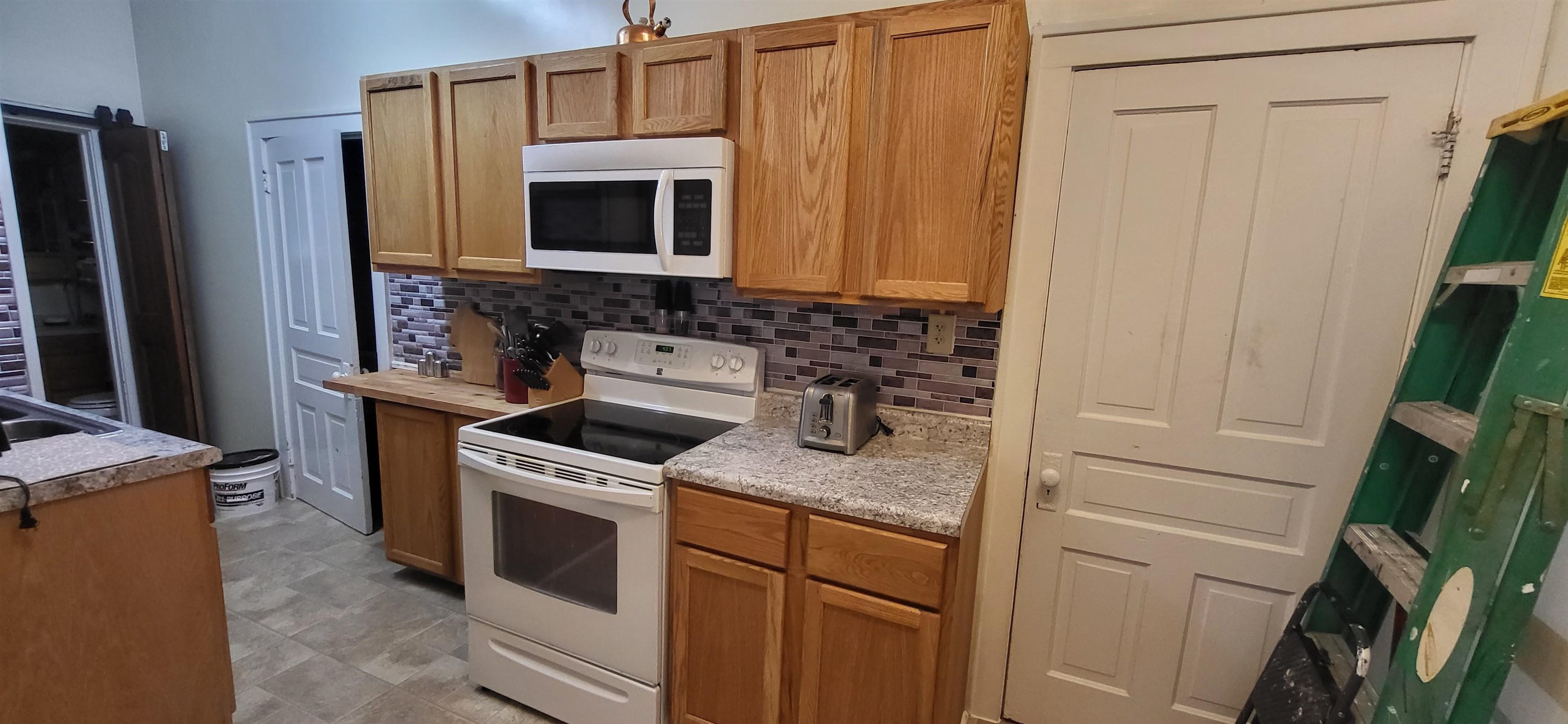 516 Main Street West Ashland, WI 54806 - Photo 8 of 11 Kitchen with white appliances, brown cabinetry, and tasteful backsplash