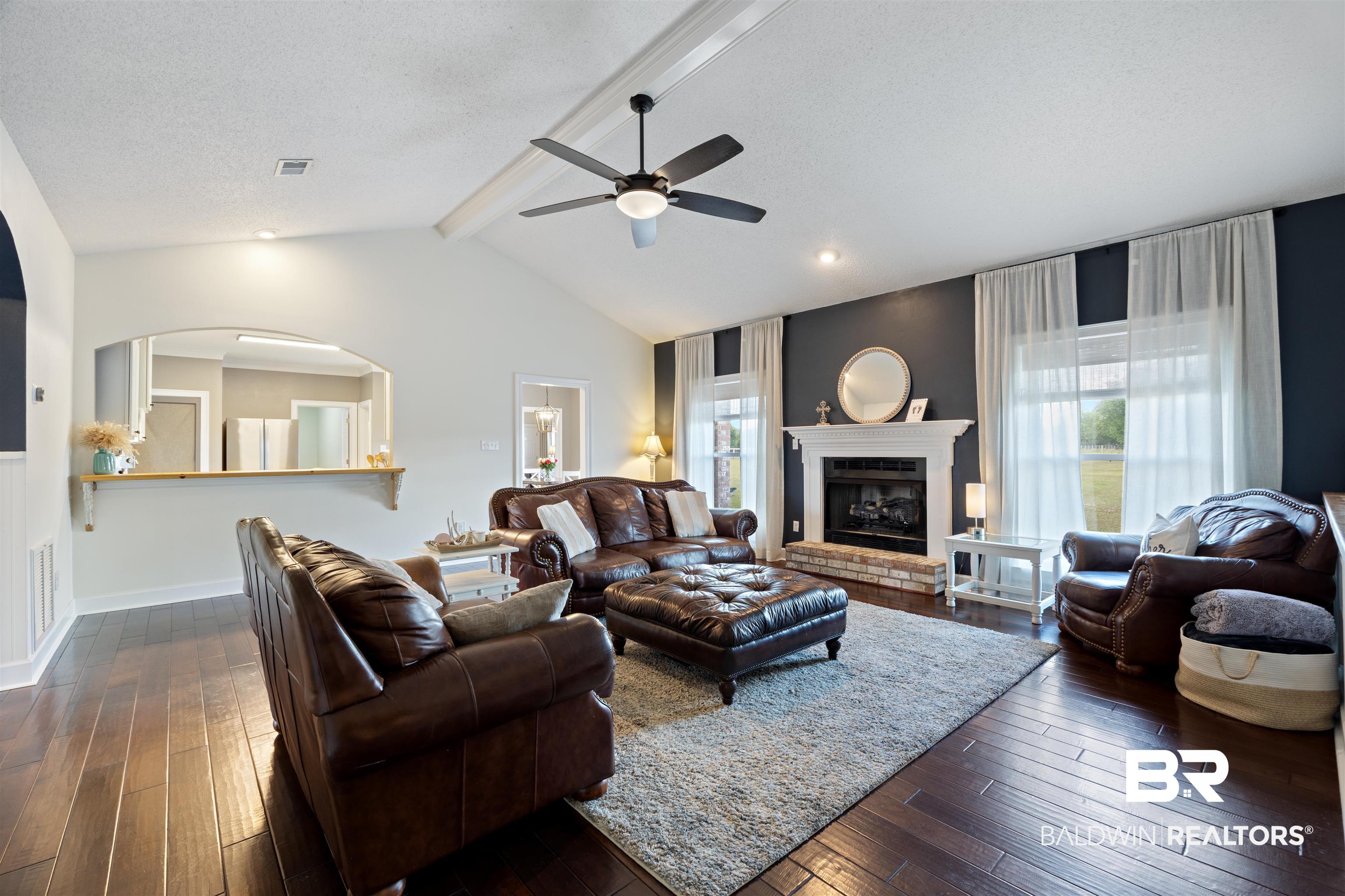9855 Stucki Road Elberta, AL 36530 - Photo 17 of 54 Living room featuring dark wood-type flooring, ceiling fan, beamed ceiling, a fireplace, and plenty of natural light
