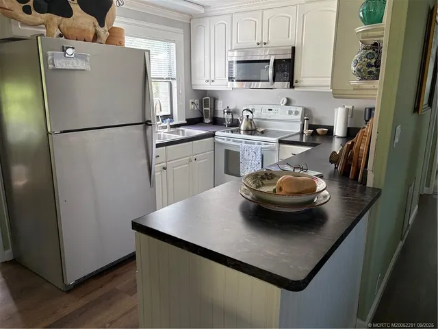 a kitchen with stainless steel appliances kitchen island granite countertop a refrigerator a stove a sink a microwave and cabinets