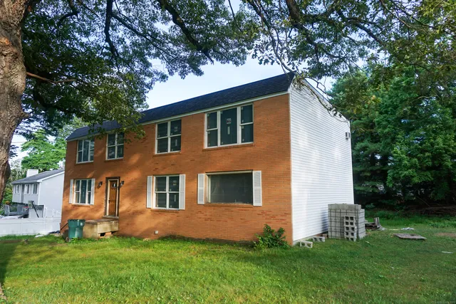 a front view of a house with a yard and tree