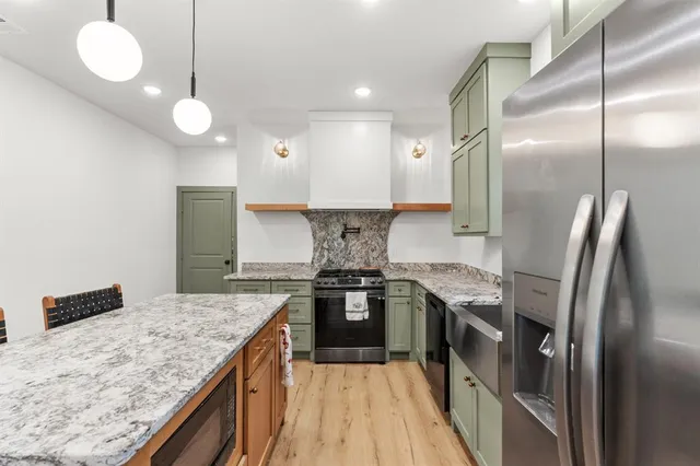 a kitchen with stainless steel appliances granite countertop a sink and a refrigerator