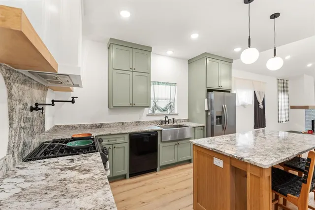a kitchen with stainless steel appliances kitchen island granite countertop a sink stove and refrigerator