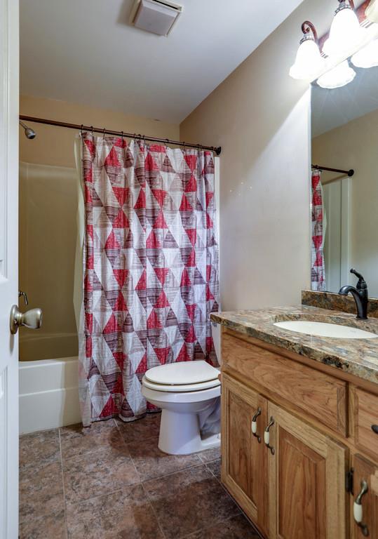 5056 Joe Peay Road Spring Hill, TN 37174 - Photo 23 of 30 a bathroom with a granite countertop sink a toilet and a mirror
