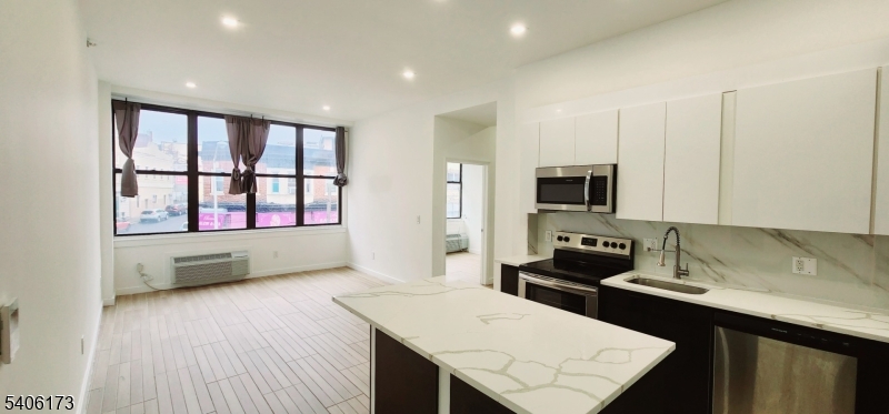 30 Howe Avenue Passaic, NJ 07055 - Photo 3 of 6 a kitchen with stainless steel appliances kitchen island granite countertop a stove a sink and a microwave