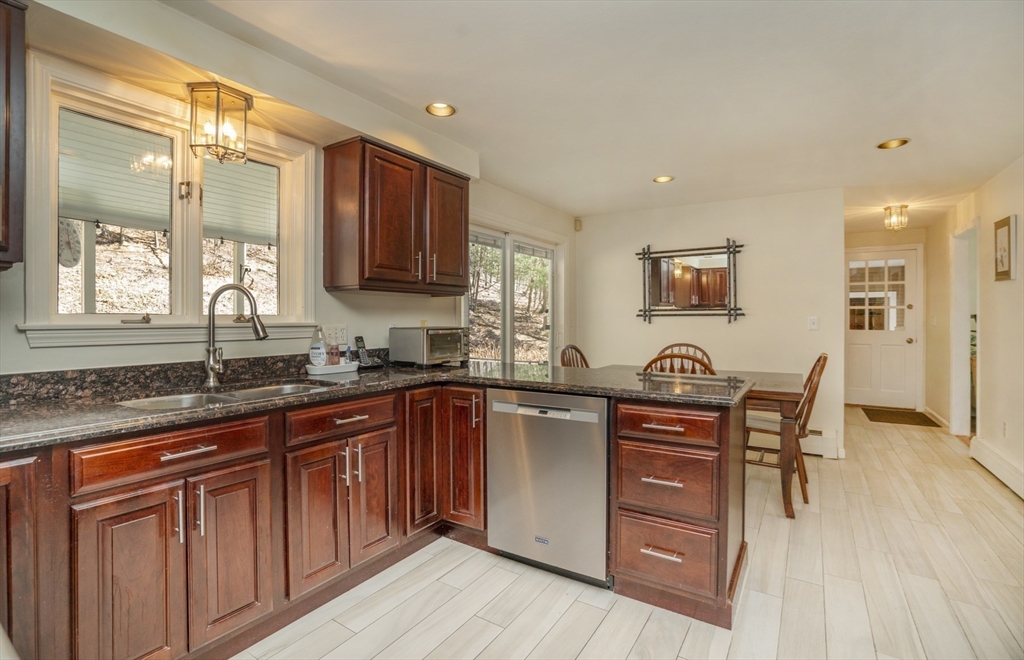 22 Elizabeth Street Amesbury, MA 01913 - Photo 4 of 38 a kitchen with stainless steel appliances granite countertop wooden floors wooden cabinets a sink and a window