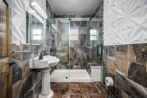 a bathroom with a sink and mirror with bathtub
