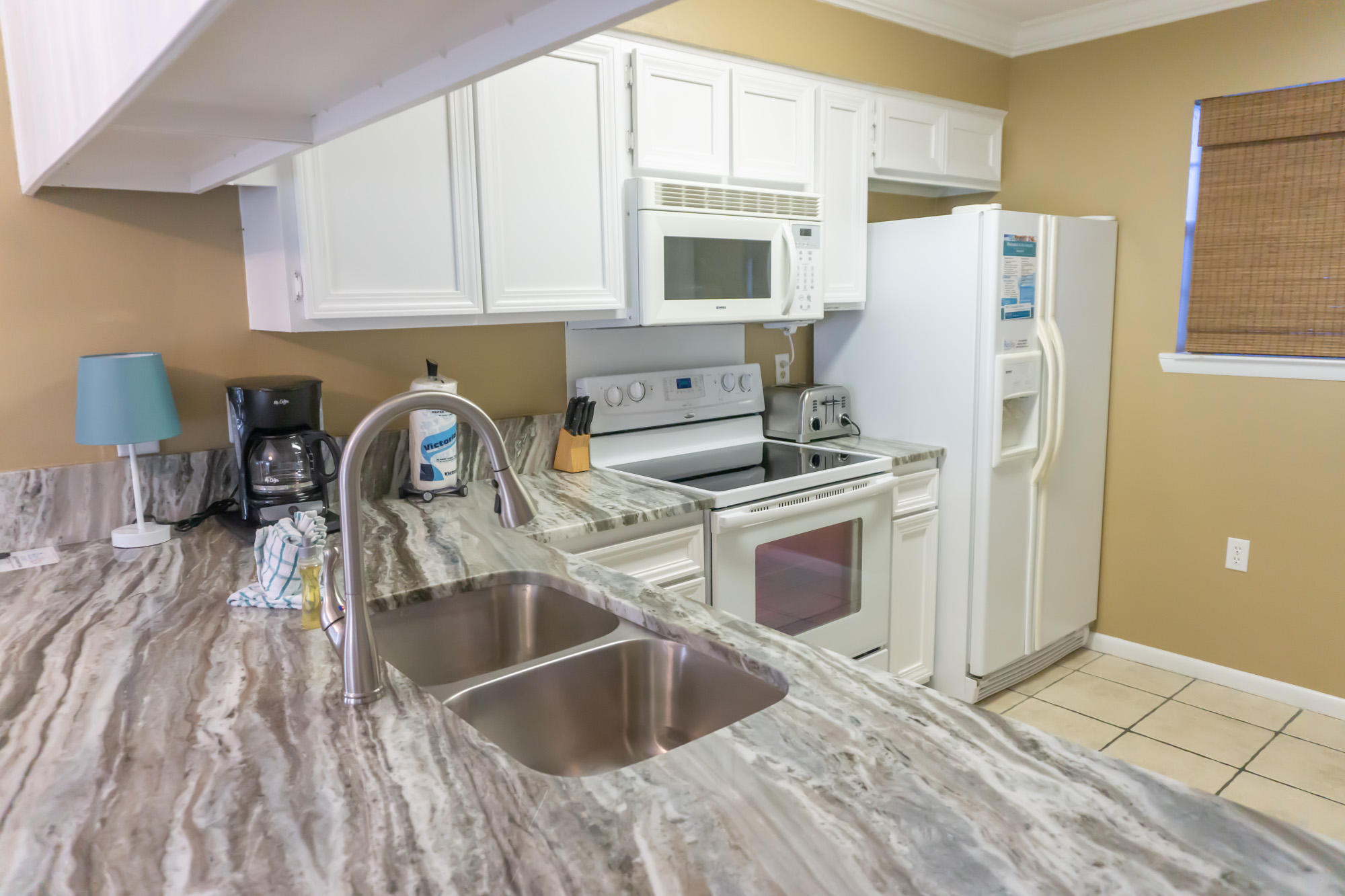 2000 Scenic Gulf Drive, Unit 5 Miramar Beach, FL 32550 - Photo 10 of 54 a kitchen with a refrigerator sink and white cabinets