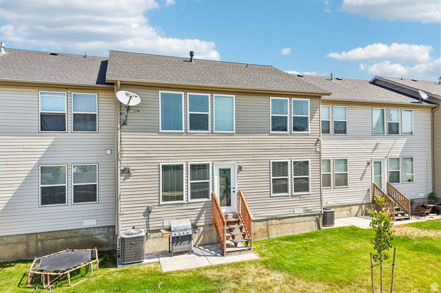 3215 West 450 North West Point, UT 84015 - Photo 29 of 40 Rear exterior featuring light-colored siding, multiple windows, a ground-level patio, and wood stairs leading to an upper-level door