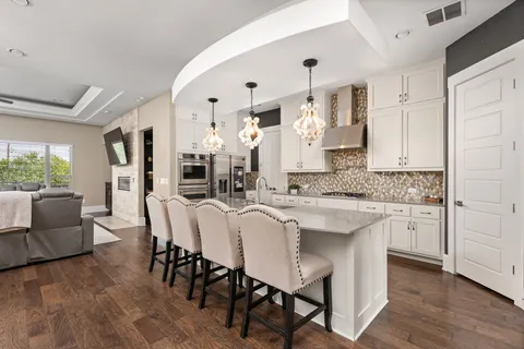a kitchen with stainless steel appliances granite countertop a table chairs sink and cabinets