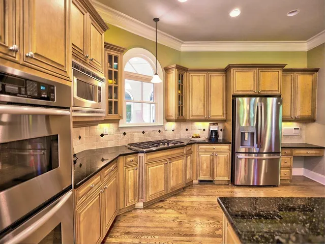 a kitchen with stainless steel appliances granite countertop wooden floors and white cabinets