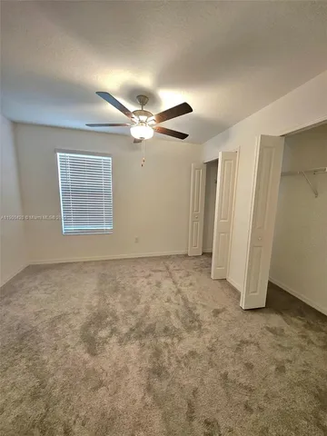 an empty room with a ceiling fan and window