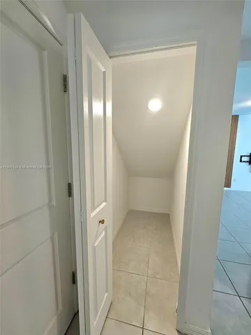 an empty room with mirror and a bathroom