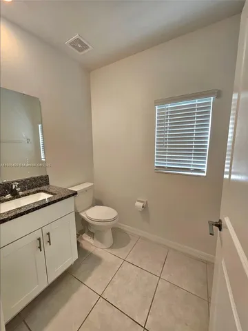 a bathroom with a granite countertop toilet a sink a mirror and a shower