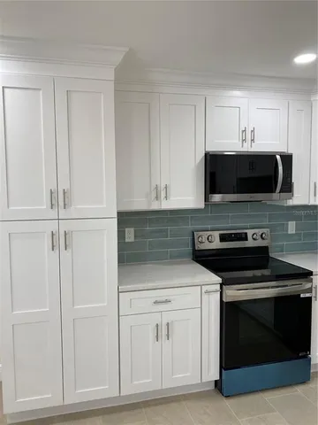 a kitchen with white cabinets and stainless steel appliances