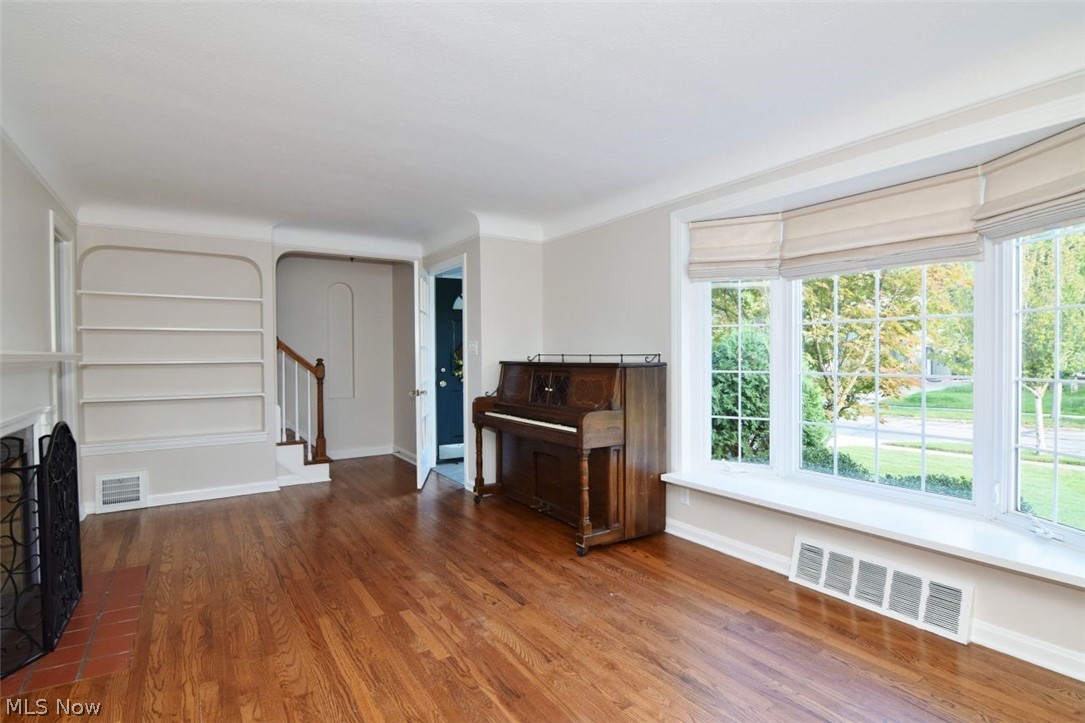 5284 Edenhurst Road Lyndhurst, OH 44124 - Photo 7 of 50 Hardwood flooring, bay windows, built-in shelving, staircase with wood handrail, and white trim work