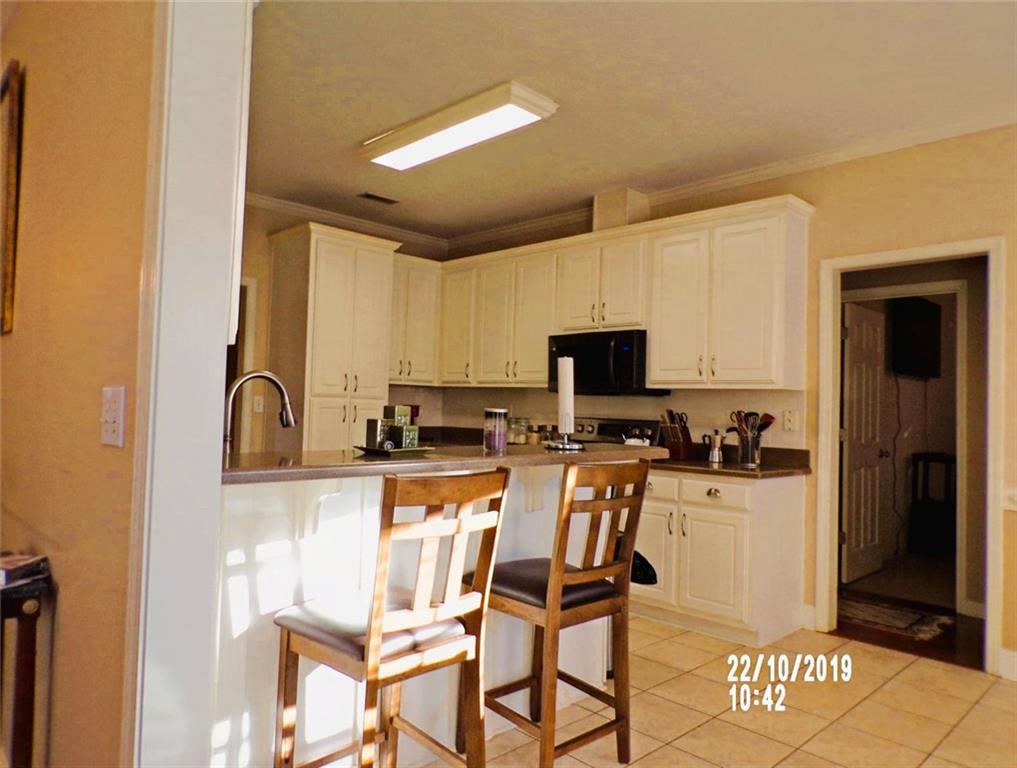 1035 Upchurch Road McDonough, GA 30252 - Photo 7 of 48 a kitchen with stainless steel appliances kitchen island granite countertop a stove a sink a refrigerator and white cabinets with wooden floor