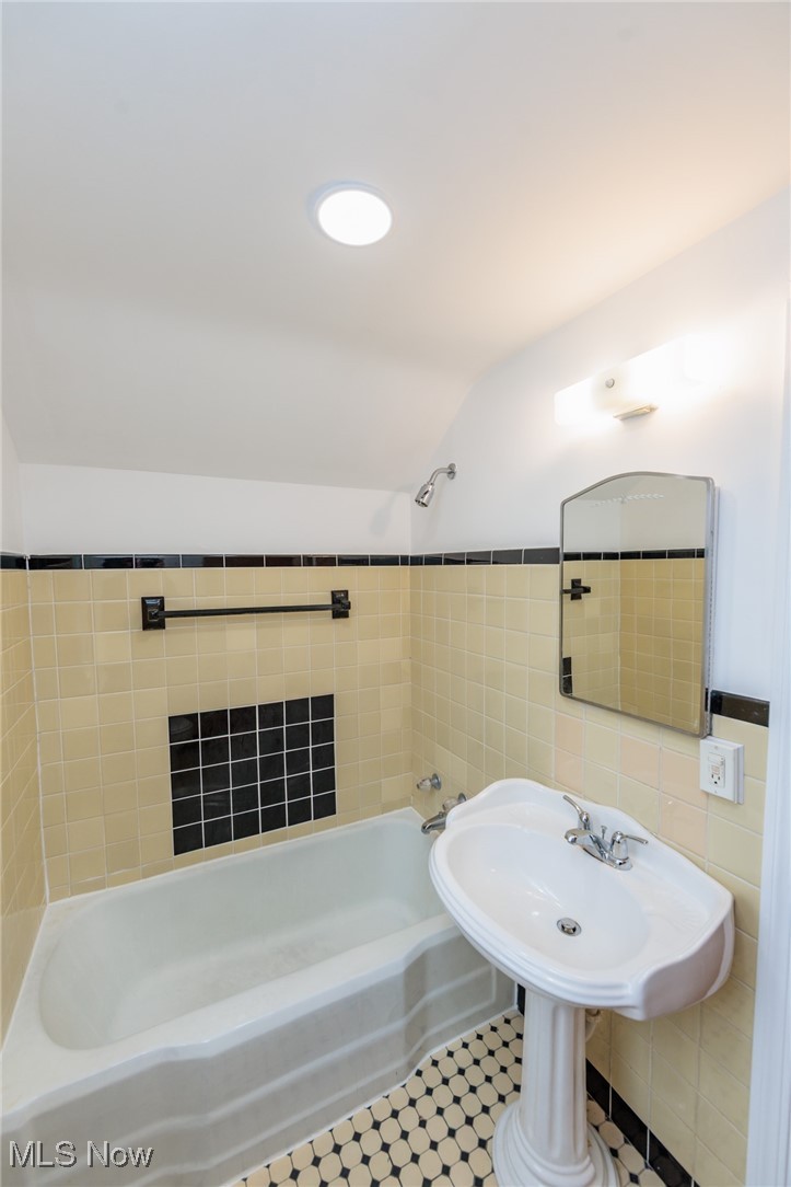 1232 Avondale Road Cleveland, OH 44121 - Photo 23 of 46 Full bathroom with lofted ceiling, shower / bathing tub combination, and tile walls