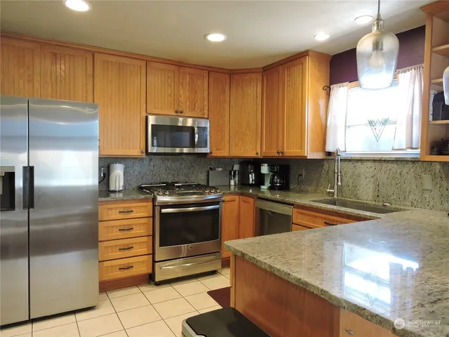 a kitchen with stainless steel appliances granite countertop a sink a stove and a refrigerator
