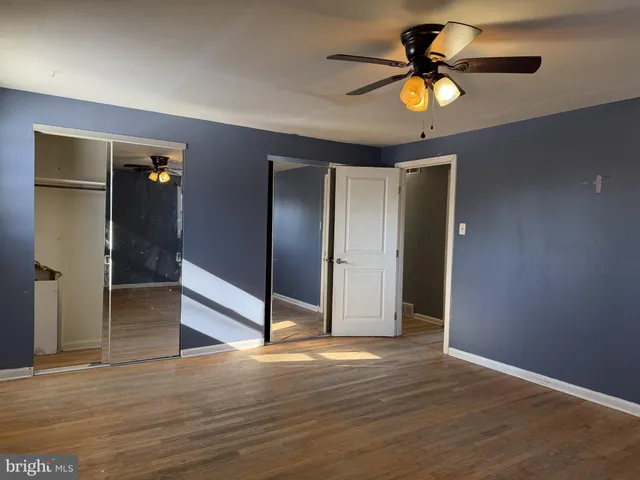an empty room with wooden floor and chandelier fan