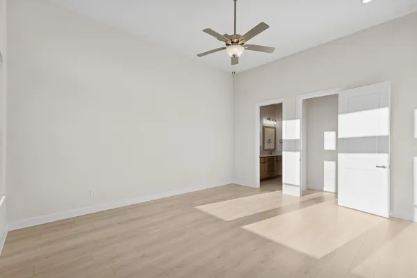 an empty room with a bathroom and a chandelier fan