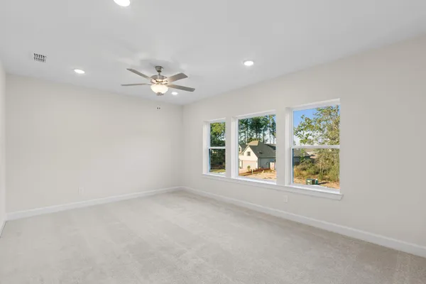 an empty room with windows and ceiling fan