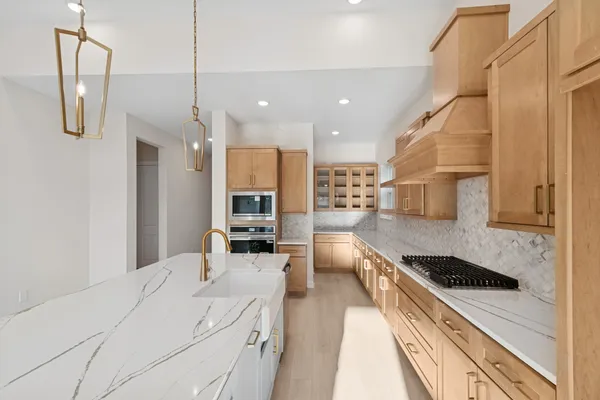 a kitchen with stainless steel appliances a stove a sink a refrigerator white cabinets and couches