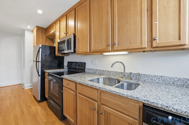 a kitchen with stainless steel appliances granite countertop a sink a stove and refrigerator