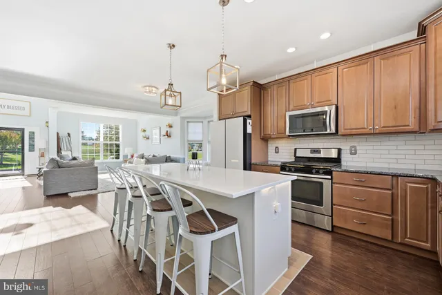 a kitchen with stainless steel appliances granite countertop a stove a sink a microwave a refrigerator a stove a dining table and chairs with wooden floor