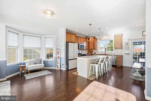 a living room with stainless steel appliances kitchen island granite countertop a couch a dining table and chairs