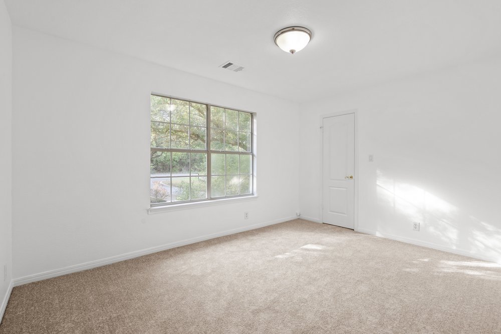 1815 Rue De St Tropez Austin, TX 78746 - Photo 35 of 40 Spacious room featuring neutral carpet flooring, white walls, a large window with grid panes, and a flush-mount ceiling light fixture