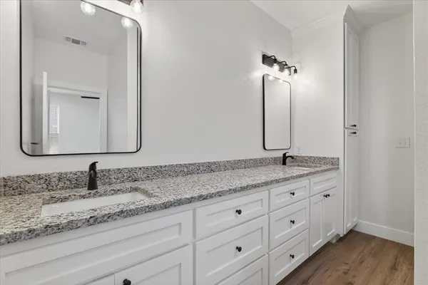 a bathroom with a granite countertop double vanity sink and mirror