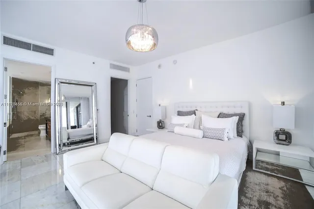 a bedroom with a large bed and chandelier