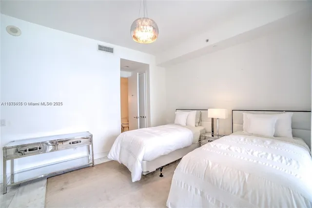 a bedroom with two bed and a lamp