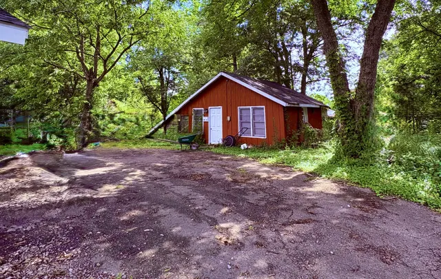 a view of a house with large trees and a yard