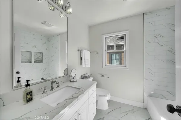 a bathroom with a granite countertop sink mirror vanity and toilet