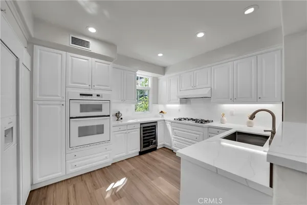 a kitchen with white cabinets stainless steel appliances and sink
