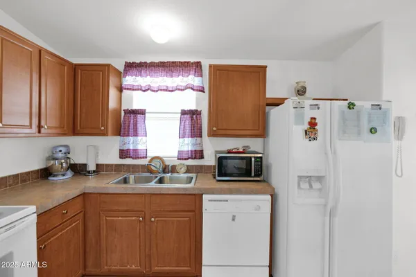 a white kitchen with a refrigerator sink and cabinets