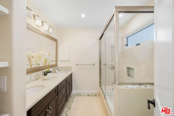 a spacious bathroom with a double vanity sink a mirror and a shower