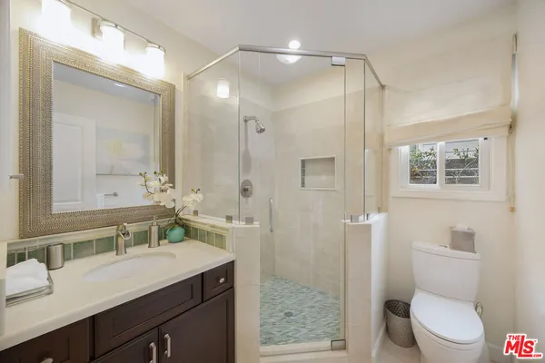 a bathroom with a sink a toilet a mirror and shower