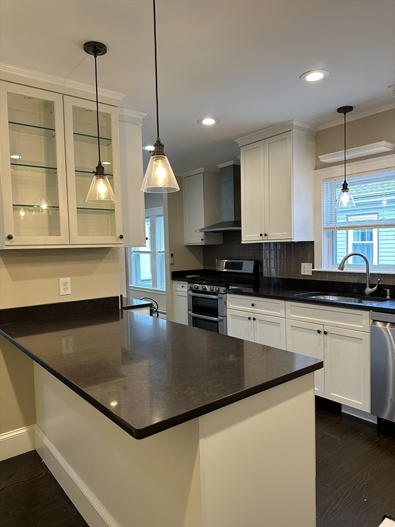a kitchen with stainless steel appliances granite countertop a sink a stove and a wooden floors