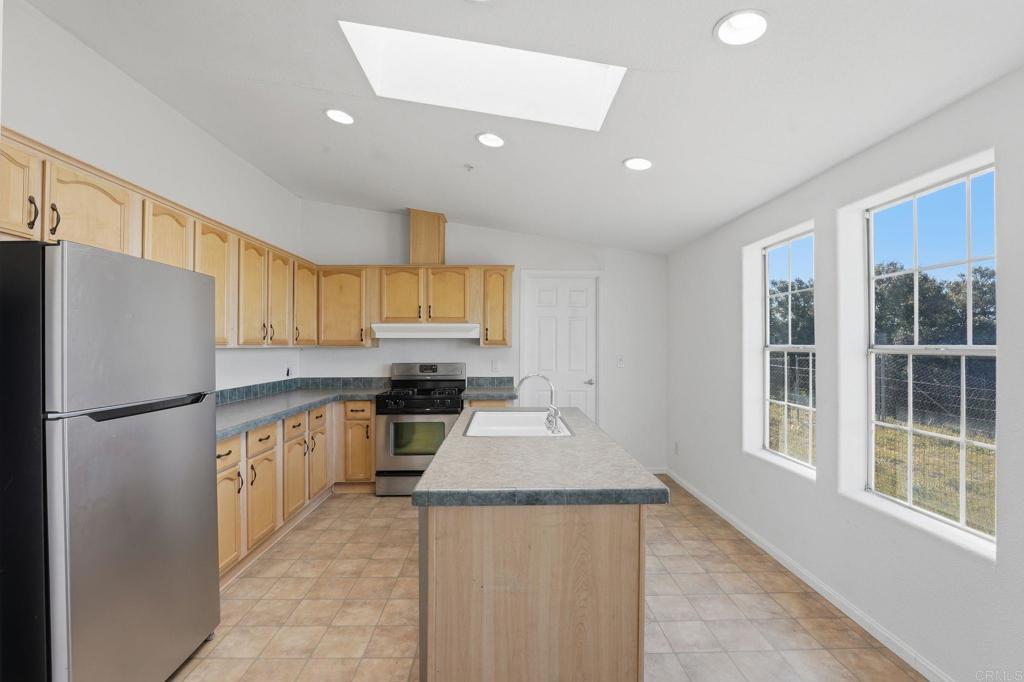 909 Tierra De Luna Road Boulevard, CA 91905 - Photo 7 of 74 a kitchen with granite countertop a refrigerator a sink a stove and white cabinets