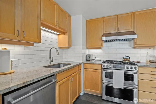 a kitchen with stainless steel appliances granite countertop a sink stove and cabinets